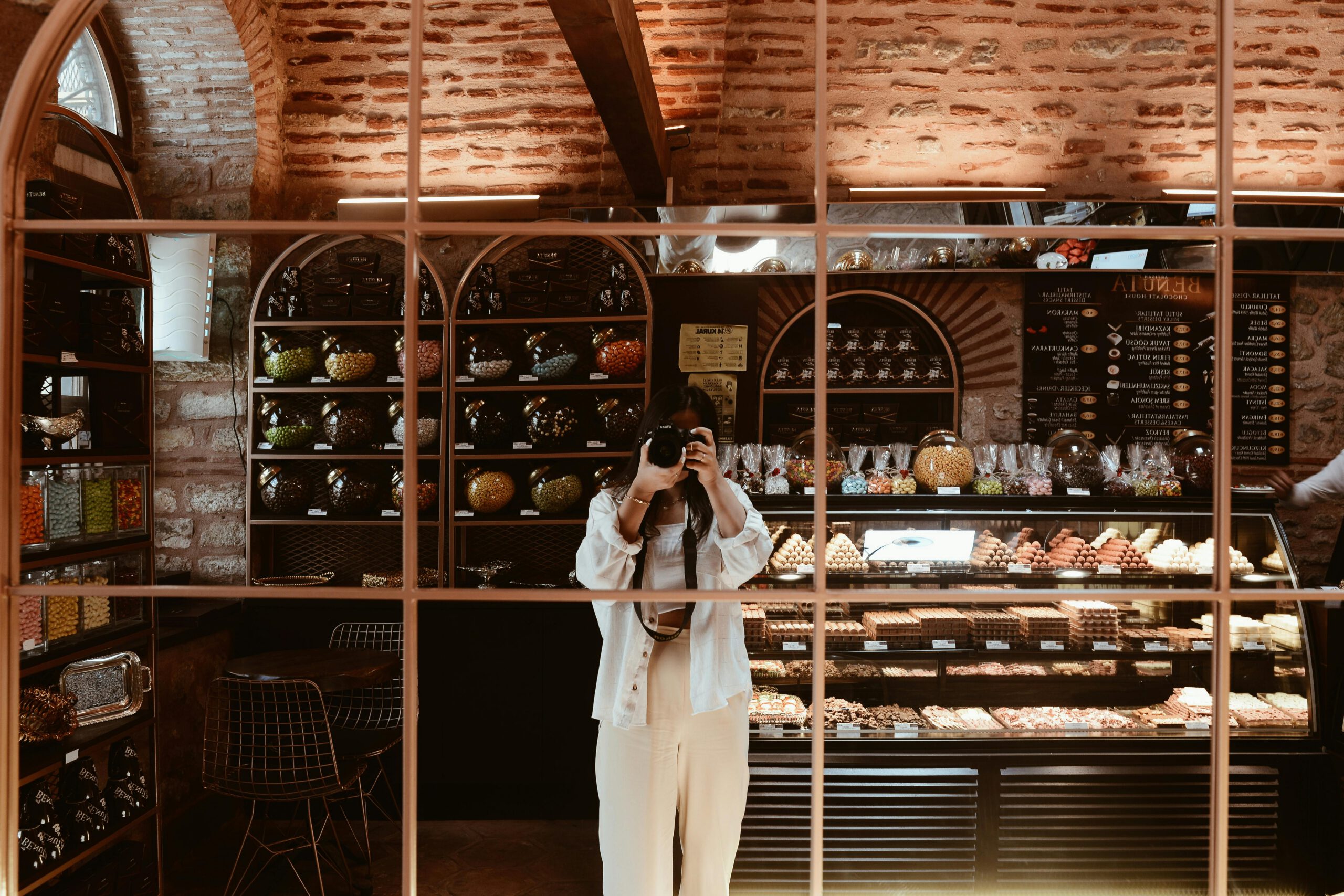 Reflection of a photographer in a cozy cafe with rustic interior and vibrant display.